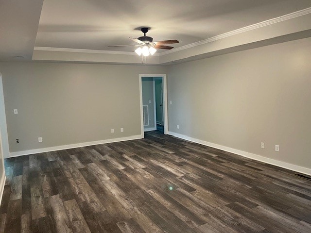 spare room featuring dark wood-type flooring, crown molding, a raised ceiling, and ceiling fan