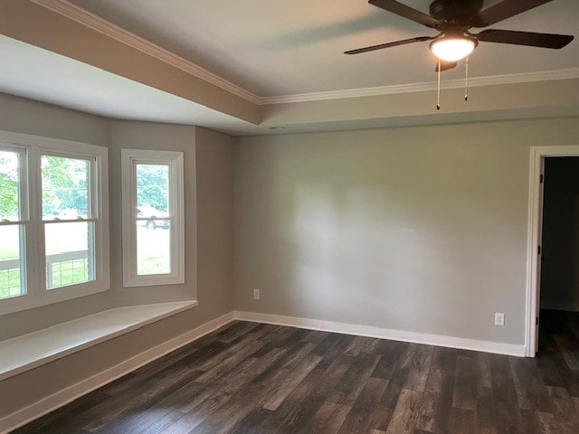 unfurnished room with a raised ceiling, ceiling fan, dark hardwood / wood-style floors, and ornamental molding