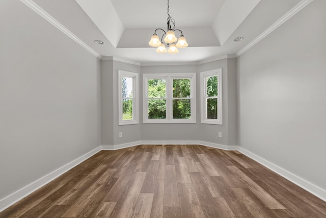 spare room featuring hardwood / wood-style flooring, crown molding, a raised ceiling, and an inviting chandelier