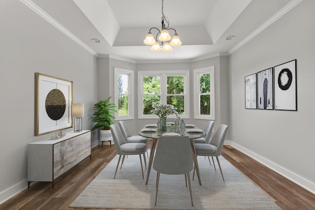 dining area with a tray ceiling, dark hardwood / wood-style flooring, crown molding, and an inviting chandelier