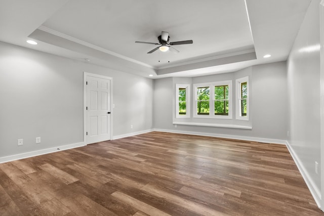 empty room featuring crown molding, wood-type flooring, and a tray ceiling