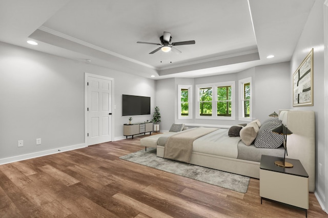 bedroom with ceiling fan, crown molding, a tray ceiling, and hardwood / wood-style floors