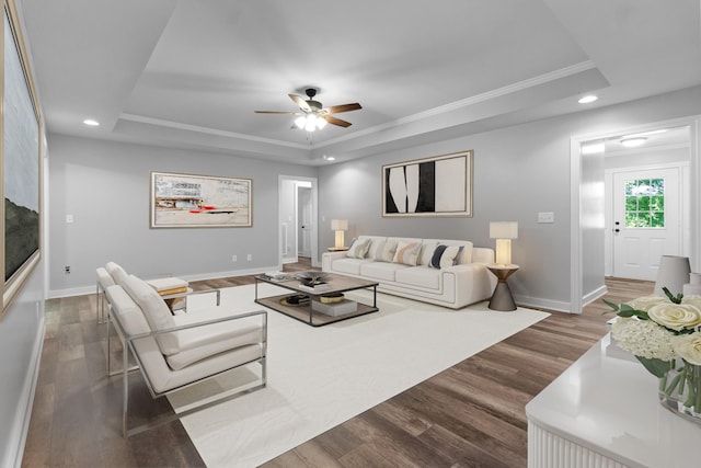 living room with crown molding, dark hardwood / wood-style flooring, and a raised ceiling