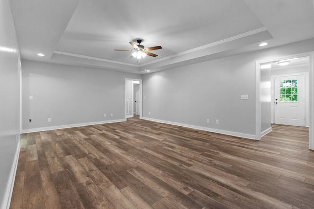 empty room featuring dark hardwood / wood-style floors, ornamental molding, and a raised ceiling