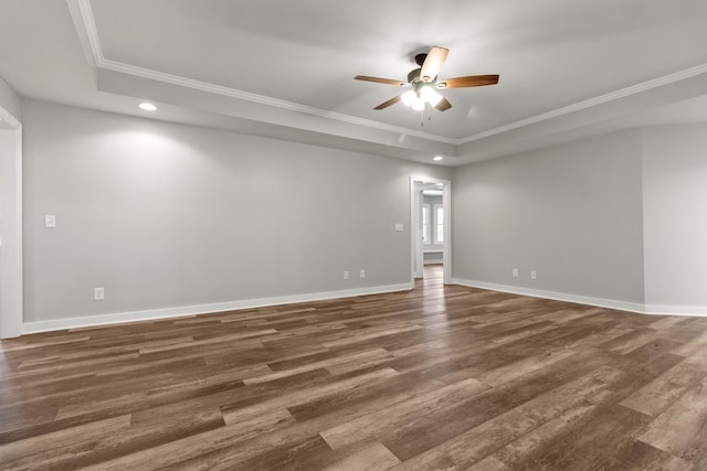 spare room featuring crown molding, ceiling fan, dark wood-type flooring, and a tray ceiling