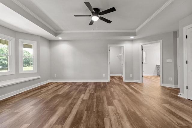 spare room featuring a raised ceiling, wood-type flooring, crown molding, and ceiling fan