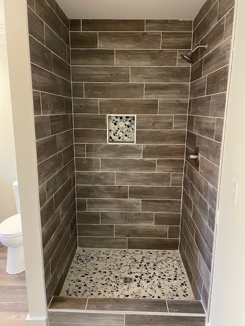 bathroom with toilet and tiled shower