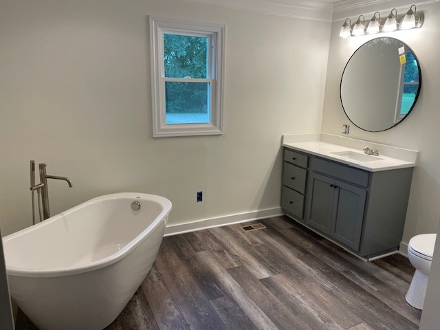 bathroom with hardwood / wood-style floors, vanity, toilet, ornamental molding, and a bathing tub