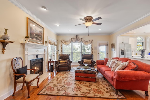 living room featuring a tile fireplace, crown molding, and light hardwood / wood-style flooring