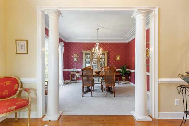 dining space with a notable chandelier, carpet flooring, ornamental molding, and decorative columns