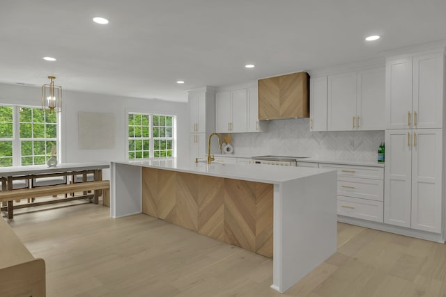 kitchen featuring white cabinetry, a healthy amount of sunlight, a center island with sink, and light hardwood / wood-style flooring