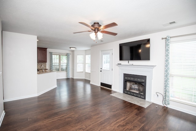 unfurnished living room with sink, dark wood-type flooring, and ceiling fan