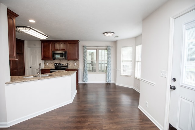 kitchen featuring dark hardwood / wood-style floors, tasteful backsplash, light stone countertops, appliances with stainless steel finishes, and sink