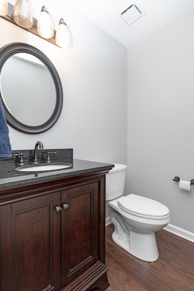 bathroom with wood-type flooring, vanity, and toilet