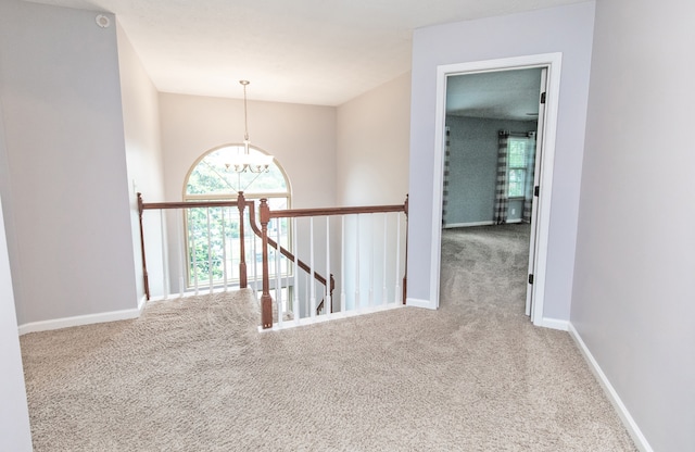 hallway with a notable chandelier and carpet floors