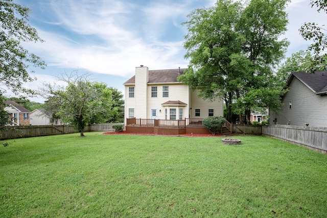 back of house with a fire pit, a wooden deck, and a yard