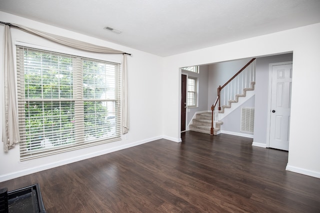 empty room featuring a healthy amount of sunlight and dark hardwood / wood-style flooring