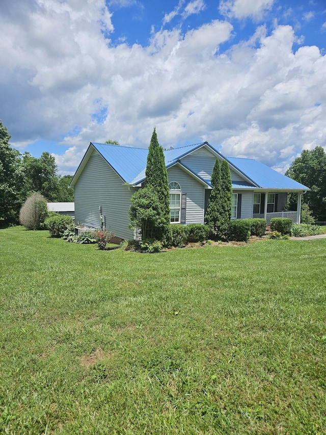 view of side of home featuring metal roof and a lawn