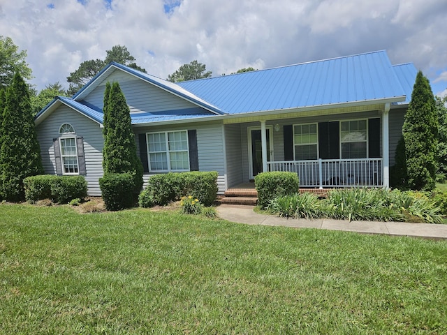 ranch-style house featuring covered porch, metal roof, and a front yard