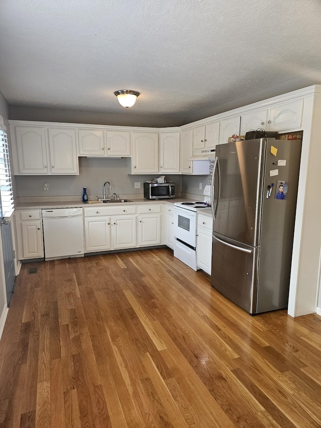 kitchen featuring hardwood / wood-style flooring, sink, white cabinetry, and stainless steel appliances