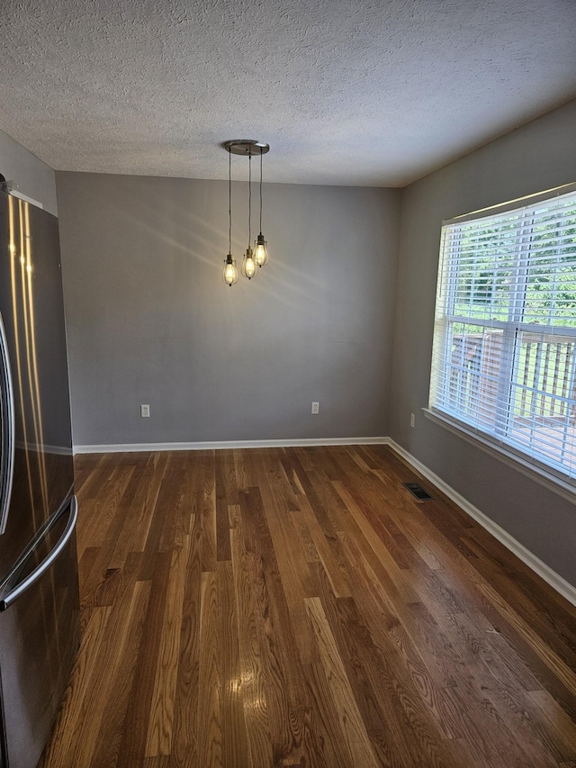 unfurnished dining area with a textured ceiling and dark hardwood / wood-style floors