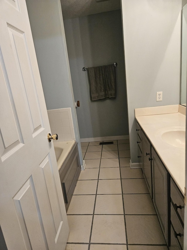 bathroom with a textured ceiling, vanity, tile patterned floors, and a bathing tub