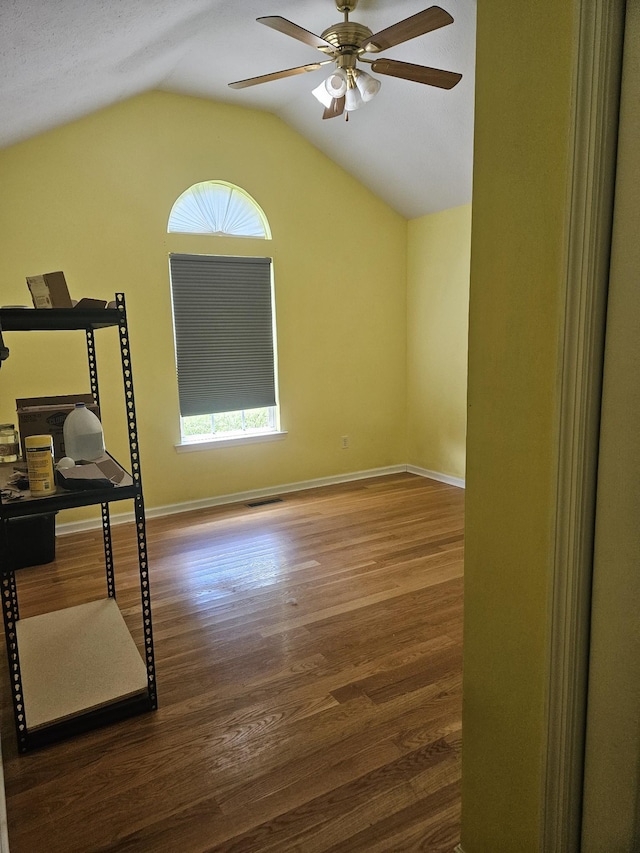 unfurnished room with baseboards, visible vents, a ceiling fan, wood finished floors, and vaulted ceiling