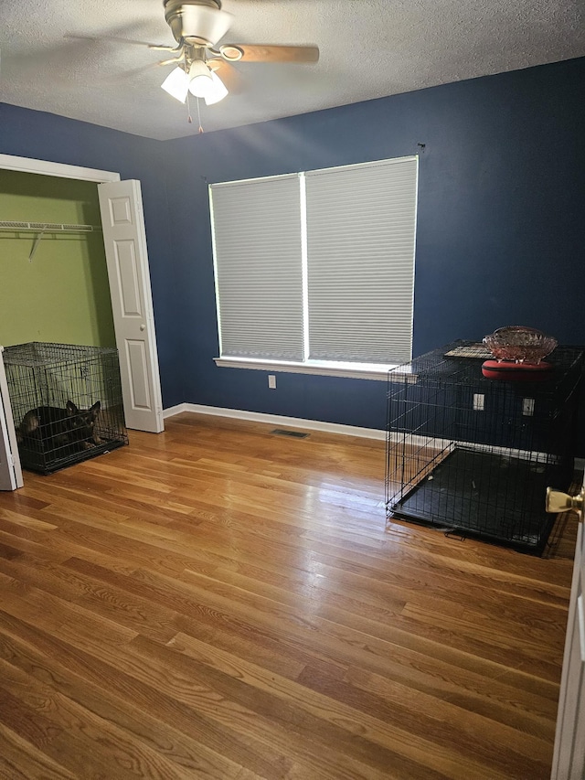 bedroom featuring a textured ceiling, ceiling fan, wood finished floors, and baseboards