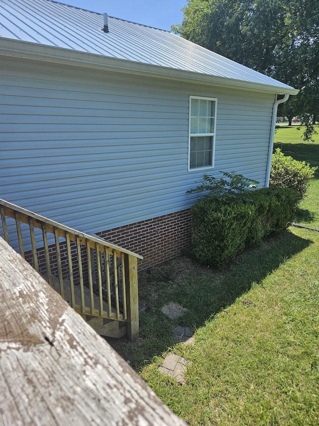 view of side of property featuring metal roof and a lawn