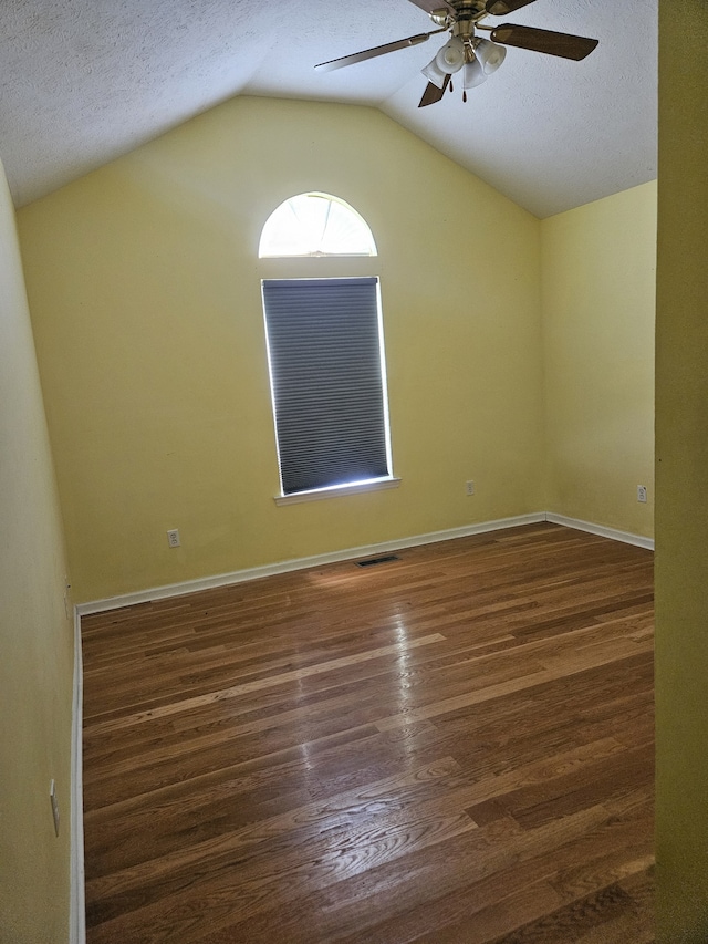 spare room with ceiling fan, dark hardwood / wood-style flooring, lofted ceiling, and a textured ceiling