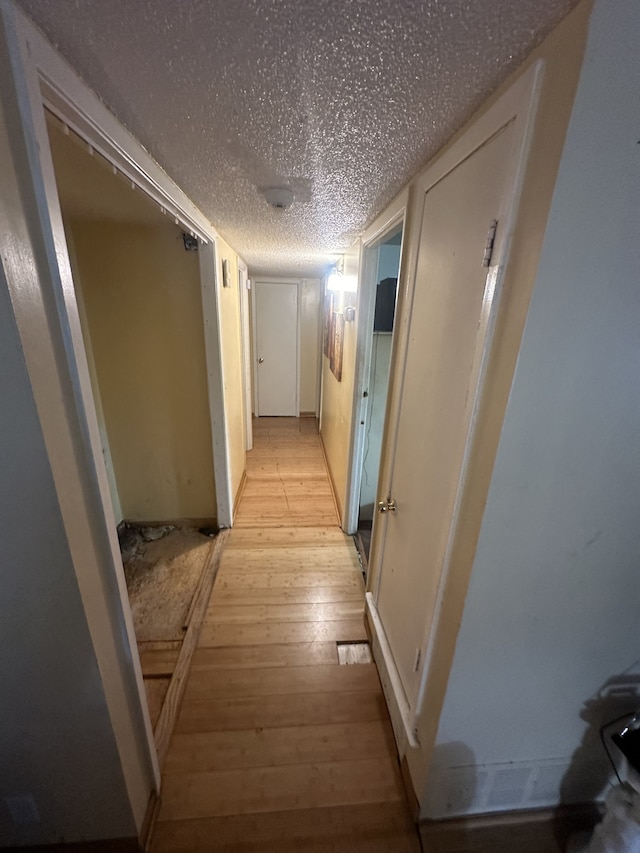 corridor with light hardwood / wood-style flooring and a textured ceiling