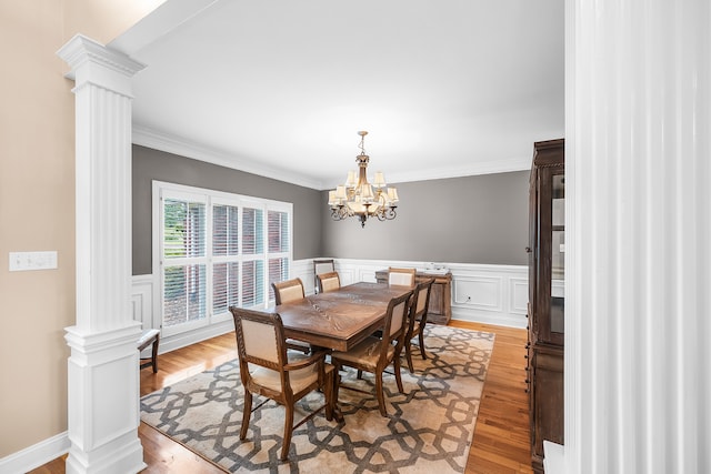 dining area featuring light hardwood / wood-style floors, decorative columns, and a chandelier