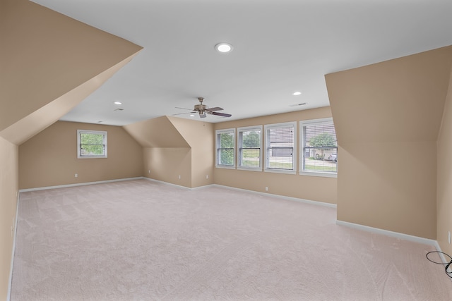 additional living space with light colored carpet, vaulted ceiling, plenty of natural light, and ceiling fan