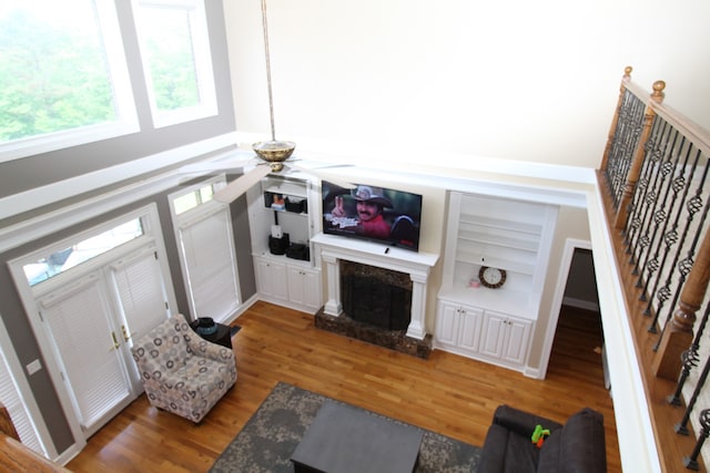 living room with wood-type flooring, built in shelves, ceiling fan, and a high end fireplace