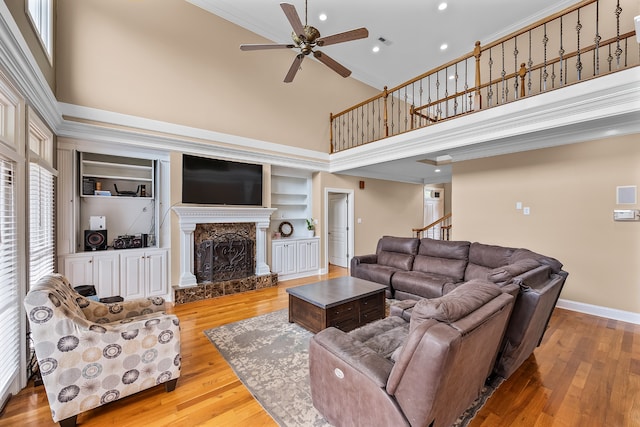 living room with a high ceiling, a high end fireplace, ceiling fan, and built in features