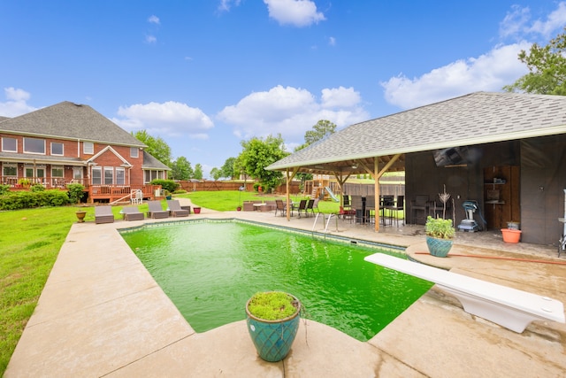 view of swimming pool with a deck, a diving board, a lawn, and a gazebo