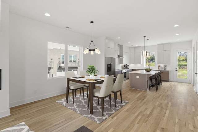 dining space featuring light hardwood / wood-style floors, plenty of natural light, and a notable chandelier