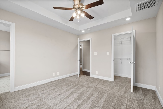 unfurnished bedroom with light carpet, a raised ceiling, ceiling fan, and a closet