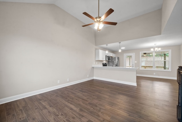 unfurnished living room featuring ceiling fan with notable chandelier, high vaulted ceiling, and dark hardwood / wood-style flooring