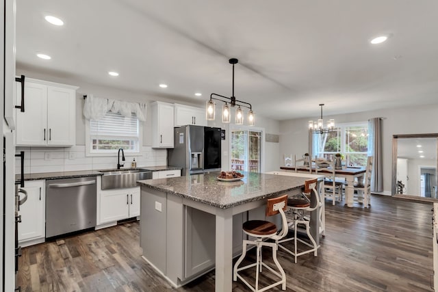 kitchen with white cabinetry, stainless steel appliances, decorative backsplash, a kitchen island, and sink