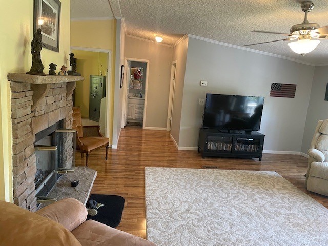 living room featuring a textured ceiling, ceiling fan, a fireplace, and hardwood / wood-style flooring