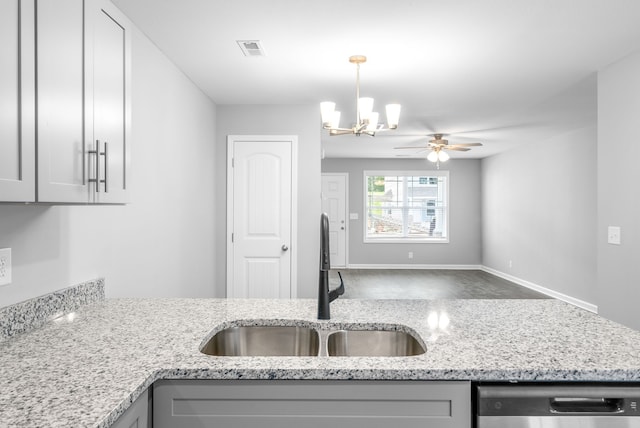 kitchen featuring ceiling fan with notable chandelier, hanging light fixtures, sink, stainless steel dishwasher, and light stone counters