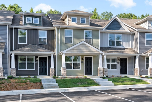 townhome / multi-family property featuring covered porch, uncovered parking, board and batten siding, and a shingled roof