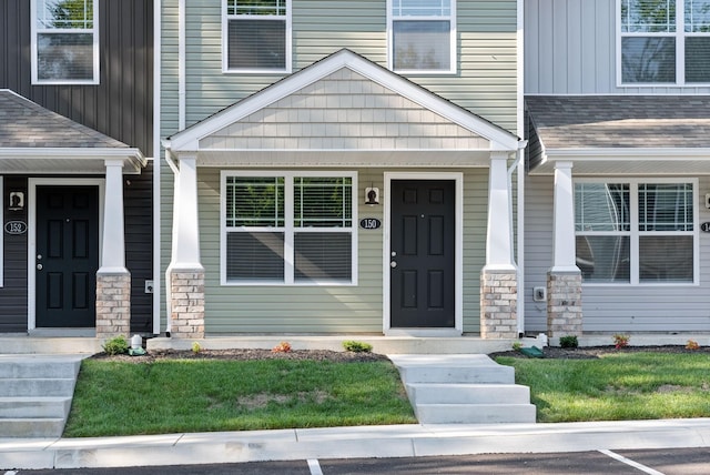 property entrance with stone siding, covered porch, board and batten siding, and roof with shingles