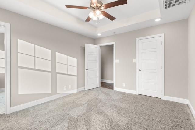 spare room featuring carpet floors, ceiling fan, and a tray ceiling