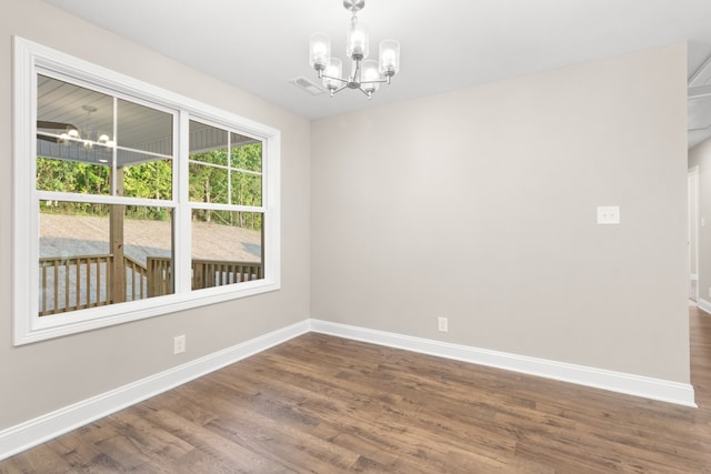 unfurnished room with dark wood-type flooring and an inviting chandelier