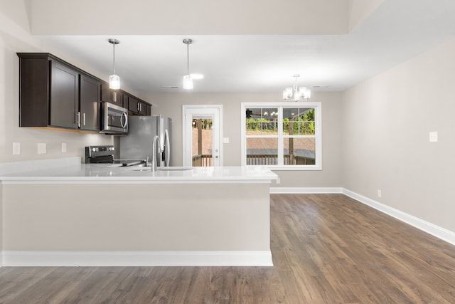 kitchen featuring dark brown cabinetry, hardwood / wood-style flooring, a notable chandelier, sink, and stainless steel appliances