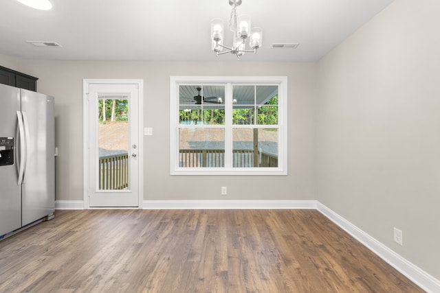 unfurnished dining area featuring hardwood / wood-style floors and an inviting chandelier