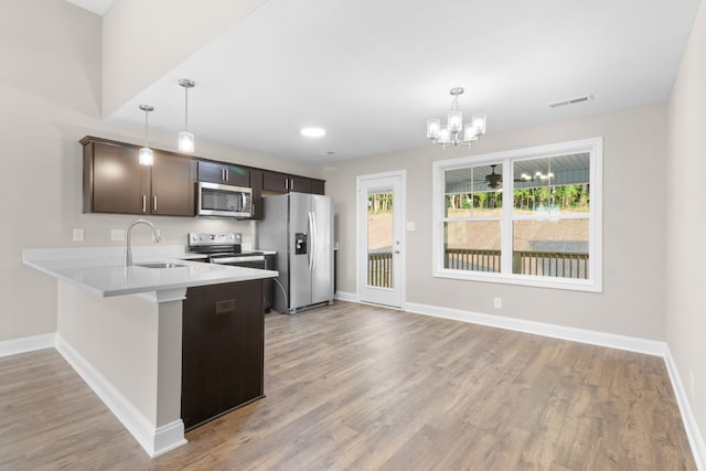 kitchen featuring appliances with stainless steel finishes, light hardwood / wood-style flooring, a wealth of natural light, and kitchen peninsula