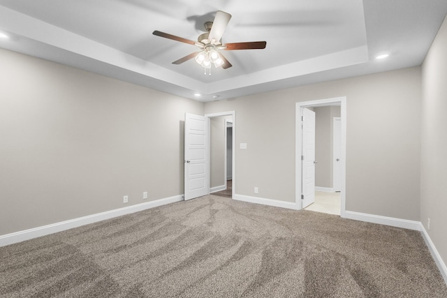 interior space with ceiling fan, carpet, and a tray ceiling